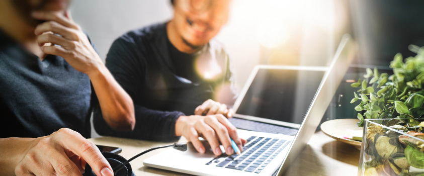 Two colleagues working together in front of a laptop